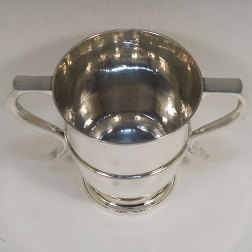 A very elegant Antique Edwardian Sterling Silver trophy loving cup, having a plain round body with a  central reeded band, two flat-topped scroll side-handles, and sitting on a round pedestal foot. This handsome antique silver loving cup trophy was made by Robert Dicker of London in 1904. The dimensions of this fine antique silver loving cup are height 14.5 cms (5.75 inches), spread across handles 21.5 cms (8.5 inches), and it weighs approx. 604g (19.5 troy ounces).   