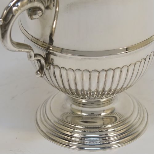 A small but fantastic quality Sterling Silver trophy cup and cover, having a round body with hand-chased half-fluted, with two cast scroll side-handles, a lift-off cover with matching decoration and a cast urn-shaped finial, and all sitting on a stepped pedestal foot. This very handsome silver trophy cup and cover was made by Henry Phillips of London in 1935. The dimensions of this fine hand-made silver trophy cup are height 15 cms (6 inches), spread across handles 14.5 cms (5.75 inches), and it weighs approx. 375g (12 troy ounces).  