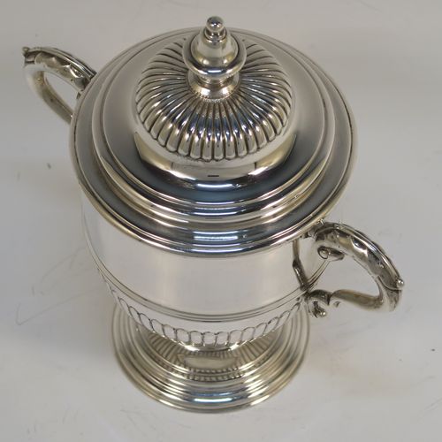 A small but fantastic quality Sterling Silver trophy cup and cover, having a round body with hand-chased half-fluted, with two cast scroll side-handles, a lift-off cover with matching decoration and a cast urn-shaped finial, and all sitting on a stepped pedestal foot. This very handsome silver trophy cup and cover was made by Henry Phillips of London in 1935. The dimensions of this fine hand-made silver trophy cup are height 15 cms (6 inches), spread across handles 14.5 cms (5.75 inches), and it weighs approx. 375g (12 troy ounces).  