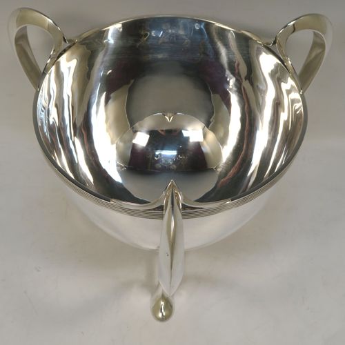 An elegant and heavy Antique Edwardian Sterling Silver three-handled Loving cup bowl, having a plain round body with tapering sides and an applied reeded top border, with three scroll side-handled feet. This handsome antique silver loving cup trophy bowl was made by Horace Woodward of London in 1903. The dimensions of this fine hand-made sterling silver trophy cup bowl are height 21 cms (8.25 inches), diameter of main body 20 cms (8 inches), and it weighs approx. 1,198g (38.6 troy ounces).  