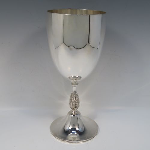 A large and handsome Antique Edwardian Silver-Plated goblet style trophy cup, having a plain round bellied body, sitting on a plain round pedestal foot with an applied bead-edged border, and with a cast floral central leaf stem. This elegant silver plated goblet trophy was made by Mappin and Webb of London in ca. 1910. The dimensions of this large and fine hand-made antique silver-plated trophy goblet cup are height 28 cms (11 inches), and diameter at lip 12 cms (4.75 inches).   