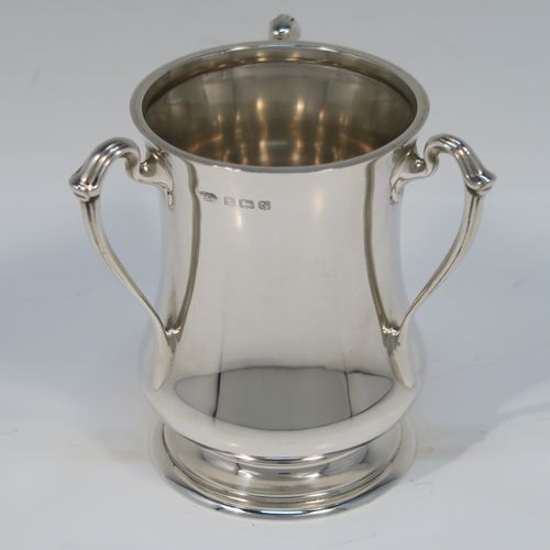 A small but but handsome Sterling Silver three-handled Loving cup, having a plain round bellied body, with three cast scroll side handles, and all sitting on a round pedestal foot. This elegant silver loving cup trophy was made by Ollivant and Botsford of Birmingham in 1937. The dimensions of this fine hand-made sterling silver trophy cup are height 9.5 cms (3.75 inches), diameter of main body 7 cms (2.75 inches), and it weighs approx. 180g (5.8 troy ounces).   