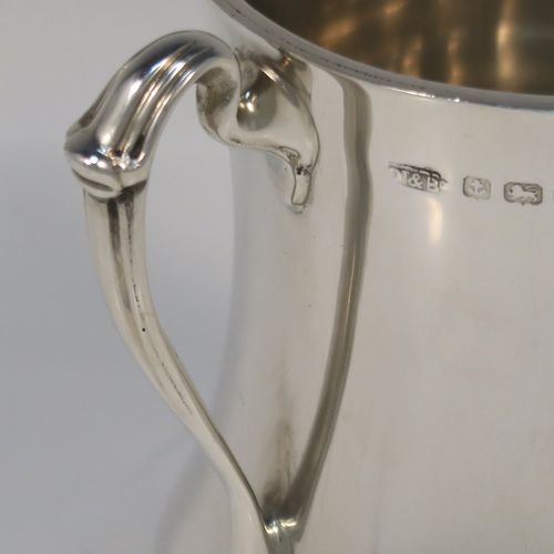 A small but but handsome Sterling Silver three-handled Loving cup, having a plain round bellied body, with three cast scroll side handles, and all sitting on a round pedestal foot. This elegant silver loving cup trophy was made by Ollivant and Botsford of Birmingham in 1937. The dimensions of this fine hand-made sterling silver trophy cup are height 9.5 cms (3.75 inches), diameter of main body 7 cms (2.75 inches), and it weighs approx. 180g (5.8 troy ounces).   