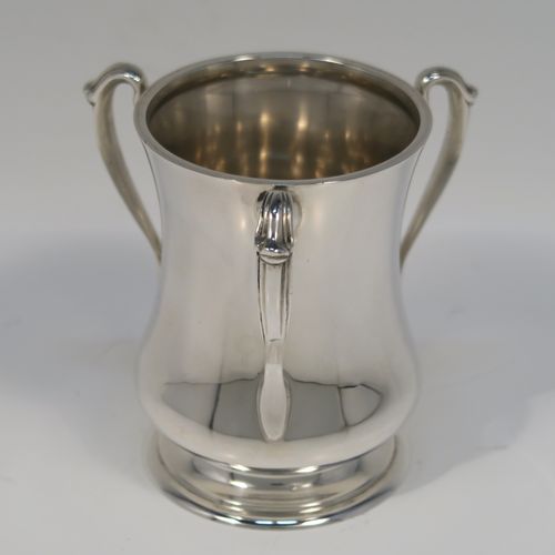 A small but but handsome Sterling Silver three-handled Loving cup, having a plain round bellied body, with three cast scroll side handles, and all sitting on a round pedestal foot. This elegant silver loving cup trophy was made by Ollivant and Botsford of Birmingham in 1937. The dimensions of this fine hand-made sterling silver trophy cup are height 9.5 cms (3.75 inches), diameter of main body 7 cms (2.75 inches), and it weighs approx. 180g (5.8 troy ounces).   