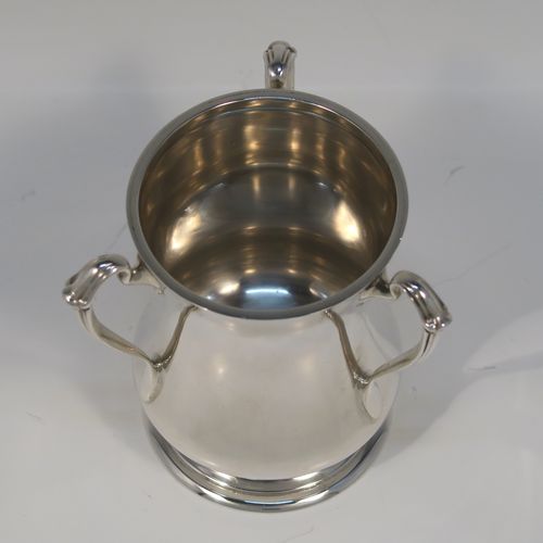 A small but but handsome Sterling Silver three-handled Loving cup, having a plain round bellied body, with three cast scroll side handles, and all sitting on a round pedestal foot. This elegant silver loving cup trophy was made by Ollivant and Botsford of Birmingham in 1937. The dimensions of this fine hand-made sterling silver trophy cup are height 9.5 cms (3.75 inches), diameter of main body 7 cms (2.75 inches), and it weighs approx. 180g (5.8 troy ounces).   