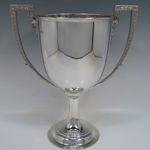 A large and handsome Antique Victorian Sterling Silver trophy cup in a George III neoclassical style, having a plain round body with tapering sides, two cast flat-topped side-handles with hand-chased oak-leaf decoration, and all sitting on a plain round stepped pedestal foot. This handsome silver trophy cup was made by Charles Boyton of London in 1898. The dimensions of this fine hand-made antique silver trophy cup are height 32 cms (12.5 inches), spread across arms 26.5 cms (10.5 inches), and it weighs approx. 1,232g (39.7 troy ounces).   