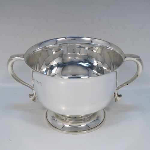 A very handsome Antique Sterling Silver trophy cup, having a plain round bellied body, with two scroll side-handles, and all sitting on a round pedestal foot. This elegant antique sterling silver trophy cup was made by William Hutton of Birmingham in 1912. The dimensions of this fine hand-made silver trophy cup are height 11 cms (4.3 inches), spread across arms 21 cms (8.25 inches), and it weighs approx. 495g (16 troy ounces).   