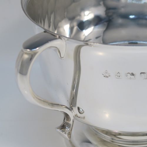 A very handsome Antique Sterling Silver trophy cup, having a plain round bellied body, with two scroll side-handles, and all sitting on a round pedestal foot. This elegant antique sterling silver trophy cup was made by William Hutton of Birmingham in 1912. The dimensions of this fine hand-made silver trophy cup are height 11 cms (4.3 inches), spread across arms 21 cms (8.25 inches), and it weighs approx. 495g (16 troy ounces).   