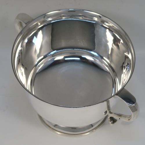 A very handsome Antique Sterling Silver trophy cup, having a plain round bellied body, with two scroll side-handles, and all sitting on a round pedestal foot. This elegant antique sterling silver trophy cup was made by William Hutton of Birmingham in 1912. The dimensions of this fine hand-made silver trophy cup are height 11 cms (4.3 inches), spread across arms 21 cms (8.25 inches), and it weighs approx. 495g (16 troy ounces).   