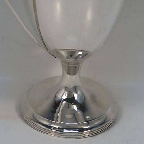 A very handsome Antique Edwardian Sterling Silver trophy cup and cover in a George III neoclassical style, having a round plain body with tapering sides, with hand-chased reeded borders, two looped side-handles, an original cover with matching decoration and cast knop finial, and all sitting on a pedestal foot. This beautiful silver trophy cup was made by Elkington and Co., of Birmingham in 1908. The dimensions of this fine hand-made silver trophy cup and cover are height 24 cms (9.5 inches), spread across arms 16.5 cms (6.5 inches), and it weighs approx. 387g (12.5 troy ounces).