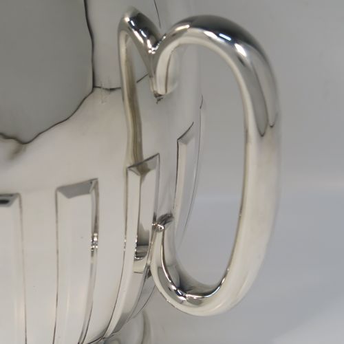 A large and handsome Antique Edwardian Sterling Silver three-handled Loving cup trophy, having a plain round bellied body with hand-chased rectangular style half-fluted decoration, together with three loop side handles, and all sitting on a round pedestal foot. This elegant silver loving cup trophy was made by Henry Woodward and Co., of London in 1902. The dimensions of this fine hand-made antique sterling silver trophy cup are height 19 cms (7.5 inches), diameter of main body 16.5 cms (6.5 inches), and it weighs approx. 844g (27 troy ounces).   