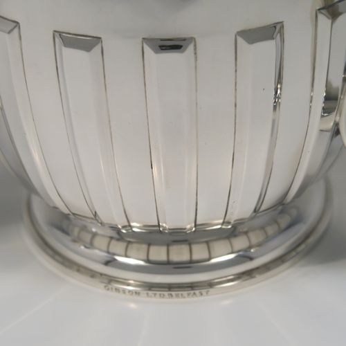 A large and handsome Antique Edwardian Sterling Silver three-handled Loving cup trophy, having a plain round bellied body with hand-chased rectangular style half-fluted decoration, together with three loop side handles, and all sitting on a round pedestal foot. This elegant silver loving cup trophy was made by Henry Woodward and Co., of London in 1902. The dimensions of this fine hand-made antique sterling silver trophy cup are height 19 cms (7.5 inches), diameter of main body 16.5 cms (6.5 inches), and it weighs approx. 844g (27 troy ounces).   