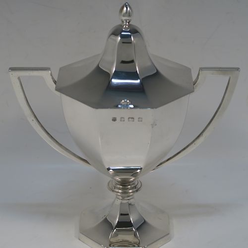 A very elegant Antique Edwardian Sterling Silver trophy cup and cover, having a plain octagonal panelled body with tapering sides, two side-handles with flat tops, an original cover with matching decoration and a pearl-drop finial, and all sitting on a panelled pedestal foot. This handsome silver trophy cup was made by A. and J. Zimmerman of Birmingham in 1909. The dimensions of this fine hand-made silver trophy cup and cover are height 18 cms (7 inches), spread across arms 16.5 cms (6.5 inches), and it weighs approx. 327g (10.5 troy ounces).   