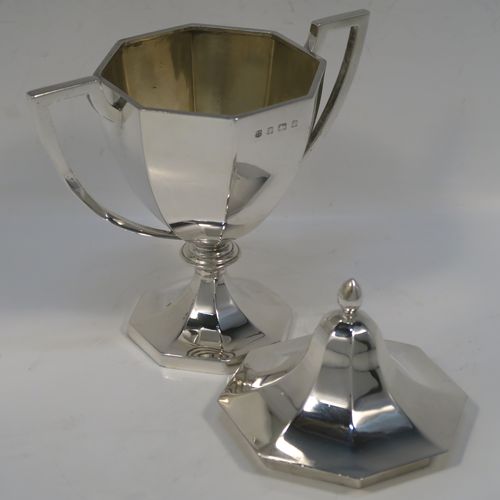 A very elegant Antique Edwardian Sterling Silver trophy cup and cover, having a plain octagonal panelled body with tapering sides, two side-handles with flat tops, an original cover with matching decoration and a pearl-drop finial, and all sitting on a panelled pedestal foot. This handsome silver trophy cup was made by A. and J. Zimmerman of Birmingham in 1909. The dimensions of this fine hand-made silver trophy cup and cover are height 18 cms (7 inches), spread across arms 16.5 cms (6.5 inches), and it weighs approx. 327g (10.5 troy ounces).
