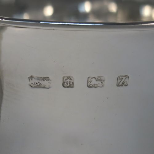 A very handsome Antique Sterling Silver trophy cup, in a George II style, having a round body with applied floral strap-work decoration, two plain scroll side-handles, a central applied girdle band, and all sitting on a stepped pedestal foot. This elegant silver trophy cup was made by Carrington and Co., of Birmingham in 1924. The dimensions of this fine hand-made antique silver trophy cup are height 20 cms (8 inches), spread across arms 27 cms (10.5 inches), and it weighs approx. 801g (25.8 troy ounces).   