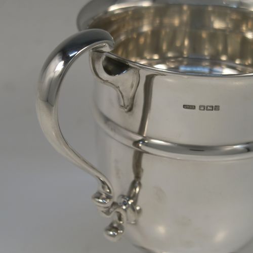 A very handsome Antique Sterling Silver trophy cup in a George III neoclassical style, having a round plain body with tapering sides and a tucked under belly, an applied central reeded band, two plain scroll side-handles, and all sitting on a stepped pedestal foot. This elegant silver trophy cup was made by George Harding and Sons of Sheffield in 1913. The dimensions of this fine hand-made silver trophy cup are height 17 cms (6.75 inches), spread across arms 20 cms (8 inches), and it weighs approx. 412g (13.3 troy ounces).