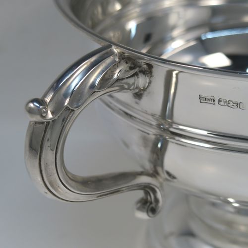 A very handsome Antique Sterling Silver trophy cup, having a plain round bellied body, with two scroll Anthemion leaf side-handles, with a central double-reeded girdle, and all sitting on a round pedestal foot. This elegant antique sterling silver trophy cup was made by Walker and Hall of Sheffield in 1919. The dimensions of this fine hand-made silver trophy cup bowl are height 15 cms (6 inches), spread across arms 31 cms (12.25 inches), and it weighs approx. 729g (23.5 troy ounces).  