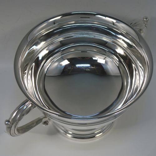 A very handsome Antique Sterling Silver trophy cup, having a plain round bellied body, with two scroll Anthemion leaf side-handles, with a central double-reeded girdle, and all sitting on a round pedestal foot. This elegant antique sterling silver trophy cup was made by Walker and Hall of Sheffield in 1919. The dimensions of this fine hand-made silver trophy cup bowl are height 15 cms (6 inches), spread across arms 31 cms (12.25 inches), and it weighs approx. 729g (23.5 troy ounces).  