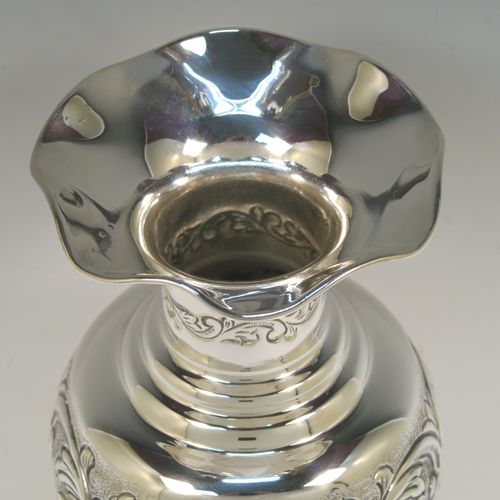 A pretty Scottish Sterling Silver large table flower vase, having a round bellied body, with hand-chased floral decoration, and sitting on a pedestal foot. This beautiful sterling silver single vase was made by the Cooper Brothers of Edinburgh in 2004. The dimensions of this fine hand-made silver vase are height 29 cms (11.5 inches), diameter of main body 12 cms (4.75 inches), and it weighs approx. 498g (16 troy ounces). Please note that this vase is not loaded.