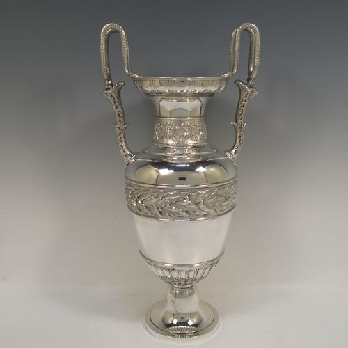 A large and heavy Antique Victorian Sterling Silver Neoclassical style single vase, having an amphora shape with a round body and hand-chased bands of floral, anthemion leaf, and fluted decoration, with two cast side handles, and all sitting on a plain round pedestal foot. This beautiful large antique silver vase was made by William Hutton and Sons of London in 1893. The dimensions of this fine hand-made antique silver vase are height 39 cms (15.3 inches), spread across arms 19 cms (7.5 inches), diameter of body at widest point 15 cms (6 inches), and it weighs approx. 1,117g (36 troy ounces). Please note that this vase is not loaded.   