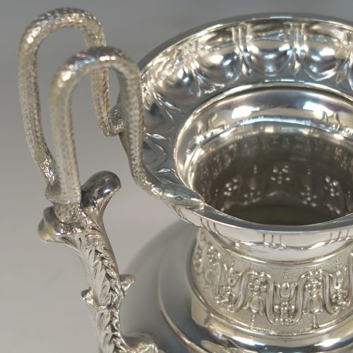 A large and heavy Antique Victorian Sterling Silver Neoclassical style single vase, having an amphora shape with a round body and hand-chased bands of floral, anthemion leaf, and fluted decoration, with two cast side handles, and all sitting on a plain round pedestal foot. This beautiful large antique silver vase was made by William Hutton and Sons of London in 1893. The dimensions of this fine hand-made antique silver vase are height 39 cms (15.3 inches), spread across arms 19 cms (7.5 inches), diameter of body at widest point 15 cms (6 inches), and it weighs approx. 1,117g (36 troy ounces). Please note that this vase is not loaded.   