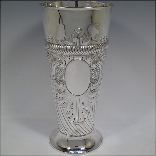A very handsome Antique Victorian Sterling Silver large table flower vase, having a tapering round body, with hand-chased swirl fluted decoration, an oval vacant cartouche surrounded by hand-chased anthemion leaves and scrolls, with an upper band of gadroon rope-twist work, and sitting on a pedestal foot. Made by Thomas Bradbury of London in 1894. The dimensions of this fine hand-made antique silver vase are height 27.5 cms (10.75 inches), diameter at top 13 cms (5 inches), and it weighs approx. 433g (14 troy ounces). Please note that this vase is not loaded.    