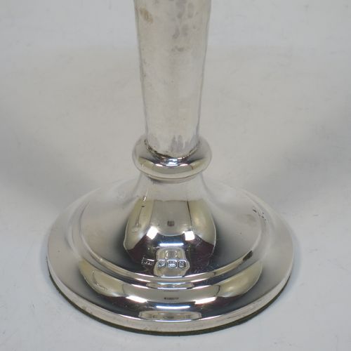 A handsome and stylish Antique Sterling Silver pair of table flower vases, having plain round tops, tapering bodies with hand-hammered decoration and oval vacant cartouches, and sitting on round stepped pedestal bases. Made by Walker and Hall of Sheffield in 1919. The dimensions of these fine hand-made pair of antique silver vases are height 22 cms (8.5 inches), and diameter at top 9 cms (3.5 inches).