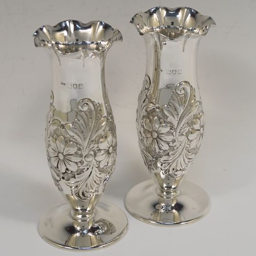 A very pretty Antique Edwardian Sterling Silver pair of table flower vases, having round hand-chased bodies with bellied sides and floral decoration, and all sitting on pedestal feet. These beautiful antique silver vases were made by Charles Edwards of London in 1902. The dimensions of these fine hand-made antique silver pair of vases are height 15 cms (6 inches), diameter at top 6 cms (2.25 inches), and they weigh at total of approx. 278g (9 troy ounces). Please note that these vases are not loaded.

  