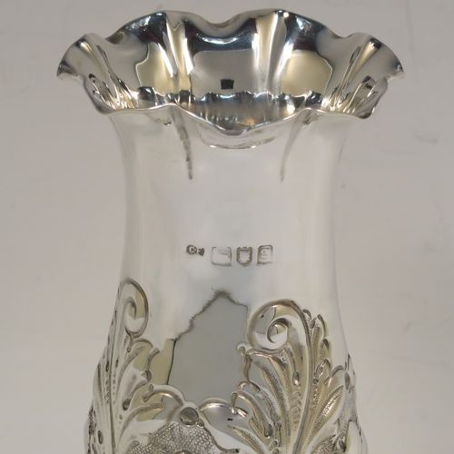 A very pretty Antique Edwardian Sterling Silver pair of table flower vases, having round hand-chased bodies with bellied sides and floral decoration, and all sitting on pedestal feet. These beautiful antique silver vases were made by Charles Edwards of London in 1902. The dimensions of these fine hand-made antique silver pair of vases are height 15 cms (6 inches), diameter at top 6 cms (2.25 inches), and they weigh at total of approx. 278g (9 troy ounces). Please note that these vases are not loaded.