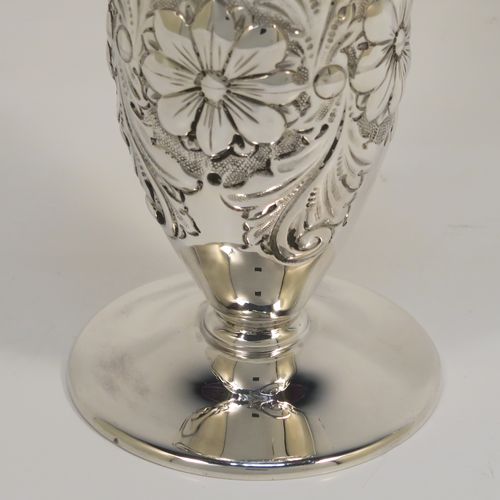 A very pretty Antique Edwardian Sterling Silver pair of table flower vases, having round hand-chased bodies with bellied sides and floral decoration, and all sitting on pedestal feet. These beautiful antique silver vases were made by Charles Edwards of London in 1902. The dimensions of these fine hand-made antique silver pair of vases are height 15 cms (6 inches), diameter at top 6 cms (2.25 inches), and they weigh at total of approx. 278g (9 troy ounces). Please note that these vases are not loaded.