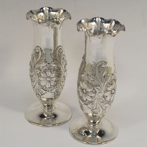 A very pretty Antique Edwardian Sterling Silver pair of table flower vases, having round hand-chased bodies with bellied sides and floral decoration, and all sitting on pedestal feet. These beautiful antique silver vases were made by Charles Edwards of London in 1902. The dimensions of these fine hand-made antique silver pair of vases are height 15 cms (6 inches), diameter at top 6 cms (2.25 inches), and they weigh at total of approx. 278g (9 troy ounces). Please note that these vases are not loaded.