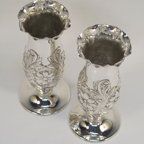 A very pretty Antique Edwardian Sterling Silver pair of table flower vases, having round hand-chased bodies with bellied sides and floral decoration, and all sitting on pedestal feet. These beautiful antique silver vases were made by Charles Edwards of London in 1902. The dimensions of these fine hand-made antique silver pair of vases are height 15 cms (6 inches), diameter at top 6 cms (2.25 inches), and they weigh at total of approx. 278g (9 troy ounces). Please note that these vases are not loaded.