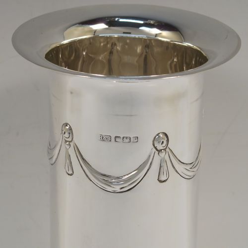 A very handsome pair of Antique Edwardian Sterling Silver table flower vases, having round straight-sided bodies with a top band of hand-chased neoclassical bow and swag style decoration, and sitting on four ball feet. These elegant silver vases were made by Roberts and Belk of Sheffield in 1907. The dimensions of these fine hand-made antique silver pair of vases are height 18.5 cms (7.25 inches), diameter at top 9 cms (3.5 inches), and they weigh at total of approx. 434g (14 troy ounces). Please note that these vases are not loaded.
