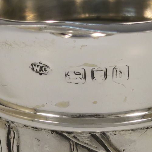 A very pretty Antique Edwardian Sterling Silver pair of table flower vases, having round hand-chased bodies with tapering sides and floral decoration, and all sitting on pedestal feet. These beautiful antique silver vases were made by William Comyns of London in 1903. The dimensions of these fine hand-made antique silver pair of vases are height 16.5 cms (6.5 inches), and diameter at top 7 cms (2.75 inches).