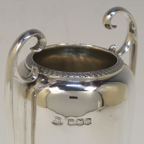 A very handsome pair of Antique Sterling Silver vases, having plain round bodies with tapering sides, with two flying scroll side handles, and applied double scroll top borders, and all sitting on round pedestal feet. These elegant silver vases were made by John Round of Sheffield in 1920. The dimensions of these fine hand-made antique silver vases are height 19 cms (7.5 inches), spread across arms 9 cms (3.5 inches), diameter of bodies at widest point 6 cms (23 inches), and they weigh approx. 354g (11.4 troy ounces). Please note that these vases are not loaded.