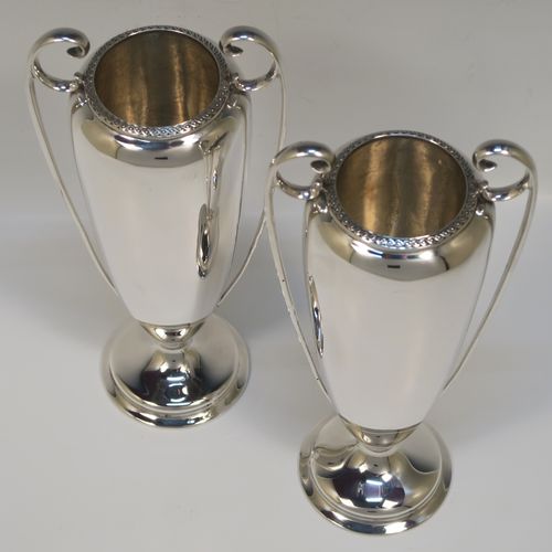 A very handsome pair of Antique Sterling Silver vases, having plain round bodies with tapering sides, with two flying scroll side handles, and applied double scroll top borders, and all sitting on round pedestal feet. These elegant silver vases were made by John Round of Sheffield in 1920. The dimensions of these fine hand-made antique silver vases are height 19 cms (7.5 inches), spread across arms 9 cms (3.5 inches), diameter of bodies at widest point 6 cms (23 inches), and they weigh approx. 354g (11.4 troy ounces). Please note that these vases are not loaded.