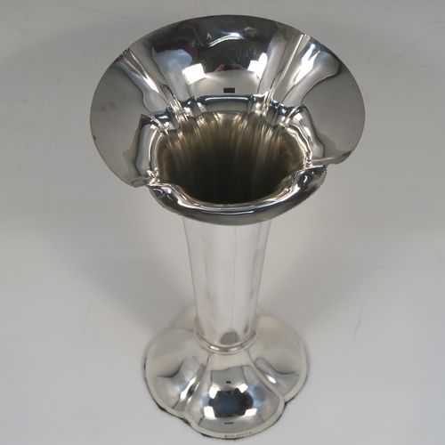 A very handsome Antique Edwardian Sterling Silver table flower vase, having a plain tapering round body with four hand-chased fluted panels, and sitting on a quattro foil pedestal foot. This elegant antique silver flower vase was made by Horace Woodward of London in 1910. The dimensions of this fine hand-made antique silver vase are height 18 cms (7 inches), and diameter at top 10 cms (4 inches).