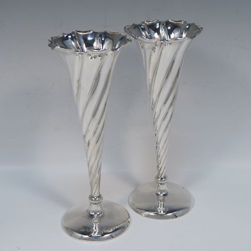 A very pretty pair of Antique Victorian Sterling Silver table flower vases, having round bodies with tapering sides and hand-chased swirl-fluted decoration, and sitting on plain round pedestal feet. These elegant silver vases were made by Stokes and Ireland of Chester in 1900. The dimensions of these fine hand-made antique silver pair of vases are height 20 cms (8 inches), and diameter at top 8 cms (3 inches).   