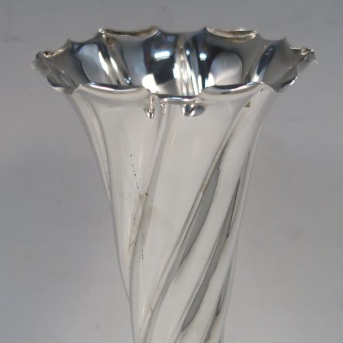 A very pretty pair of Antique Victorian Sterling Silver table flower vases, having round bodies with tapering sides and hand-chased swirl-fluted decoration, and sitting on plain round pedestal feet. These elegant silver vases were made by Stokes and Ireland of Chester in 1900. The dimensions of these fine hand-made antique silver pair of vases are height 20 cms (8 inches), and diameter at top 8 cms (3 inches).
