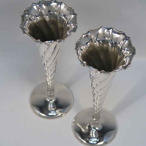A very pretty pair of Antique Victorian Sterling Silver table flower vases, having round bodies with tapering sides and hand-chased swirl-fluted decoration, and sitting on plain round pedestal feet. These elegant silver vases were made by Stokes and Ireland of Chester in 1900. The dimensions of these fine hand-made antique silver pair of vases are height 20 cms (8 inches), and diameter at top 8 cms (3 inches).