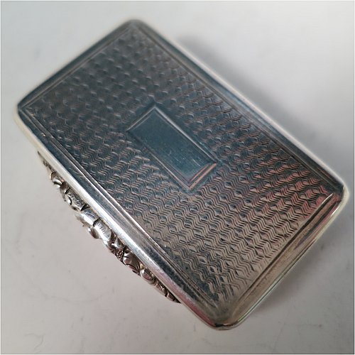 An Antique Georgian Sterling Silver vinaigrette, having machine-engraved decoration on the top and base, with hand-chased reeded edges and a cast floral thumb-piece, a gold-gilt interior, and a hand-pierced floral style grill. Made by Thomas Shaw of Birmingham in 1829. The dimensions of this fine hand-made antique silver vinaigrette are length 4 cms (1.5 inch), width 2.5 cm (1 inch), and depth 0.8 cm (0.3 inches).