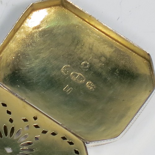 An Antique Georgian Sterling Silver vinaigrette, having a rectangular cut-cornered concave body with hand-engraved three-leaf clovers decoration on the top and floral decoration on the base, a gold-gilt interior, and a sun-motif hand-pierced grill. Made by Samuel Pemberton of Birmingham in 1809. The dimensions of this fine hand-made antique silver vinaigrette are length 4 cms (1.5 inch), width 3 cm (1.25 inch), and depth 1.2 cm (0.5 inches).