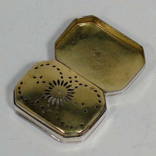 An Antique Georgian Sterling Silver vinaigrette, having a rectangular cut-cornered concave body with hand-engraved three-leaf clovers decoration on the top and floral decoration on the base, a gold-gilt interior, and a sun-motif hand-pierced grill. Made by Samuel Pemberton of Birmingham in 1809. The dimensions of this fine hand-made antique silver vinaigrette are length 4 cms (1.5 inch), width 3 cm (1.25 inch), and depth 1.2 cm (0.5 inches).