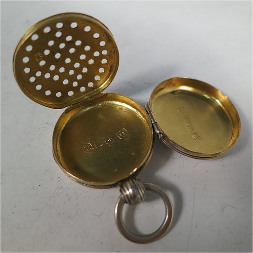 An Antique Georgian Sterling Silver vinaigrette, having a round body in the shape of a fob watch, with engine-turned decoration on the top and base, a hinged lid with ring for a chain, and a gold-gilt interior with a plain hand-pierced grill. Made by John Lawrence, of Birmingham in 1828. The dimensions of this fine hand-made antique silver vinaigrette are diameter length 2.5 cms (1 inch), and depth 0.8 cms (0.3 inches).   
