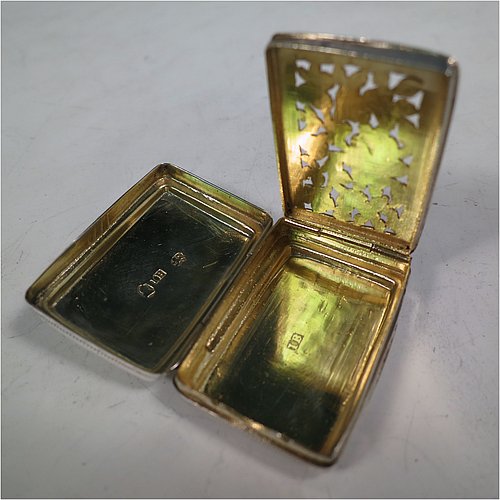 An Antique Georgian Sterling Silver vinaigrette, having a rectangular body with an applied raspberry and leaf motif surrounded by hand-engraved stipple-work on top and hand-engraved floral work on the base, a gold-gilt interior, and a hand-pierced floral grill. Made by John Bettridge of Birmingham in ca. 1820. The dimensions of this fine hand-made antique silver vinaigrette are length 3.5 cms (1.4 inches), width 2.5 cms (1 inch), and depth 1.2 cms (0.5 inch).