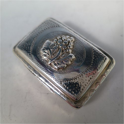 An Antique Georgian Sterling Silver vinaigrette, having a rectangular body with an applied raspberry and leaf motif surrounded by hand-engraved stipple-work on top and hand-engraved floral work on the base, a gold-gilt interior, and a hand-pierced floral grill. Made by John Bettridge of Birmingham in ca. 1820. The dimensions of this fine hand-made antique silver vinaigrette are length 3.5 cms (1.4 inches), width 2.5 cms (1 inch), and depth 1.2 cms (0.5 inch).