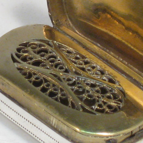 Antique Georgian sterling silver vinaigrette, having a rectangular body with rounded ends, a hand-engraved floral band of decoration, a hinged lid, and a gold-gilt interior with hinged fillagree grill. Made by Samuel Pemberton of Birmingham in 1800. The dimensions of this fine hand-made silver vinaigrette are length 3.5 cms (1.3 inches), and width 2 cms (0.75 inches).