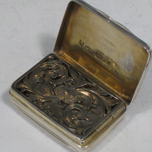 Antique Georgian sterling silver vinaigrette, having a rectangular body with hand-engraved reeded decoration and vacant cartouche, a hinged lid, a gold-gilt interior with hinged hand-pierced and chased grill with floral decoration. Made by Nathaniel Mills of Birmingham in 1828. The dimensions of this fine hand-made silver vinaigrette are length 4 cms (1.5 inches), and width 2.5 cms (1 inch).
