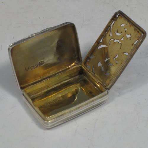 Antique Georgian sterling silver vinaigrette, having a rectangular body with hand-engraved reeded decoration and vacant cartouche, a hinged lid, a gold-gilt interior with hinged hand-pierced and chased grill with floral decoration. Made by Nathaniel Mills of Birmingham in 1828. The dimensions of this fine hand-made silver vinaigrette are length 4 cms (1.5 inches), and width 2.5 cms (1 inch).
