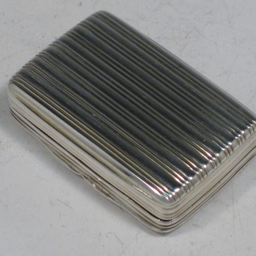 Antique Georgian sterling silver vinaigrette, having a rectangular body with hand-engraved reeded decoration and vacant cartouche, a hinged lid, a gold-gilt interior with hinged hand-pierced and chased grill with floral decoration. Made by Nathaniel Mills of Birmingham in 1828. The dimensions of this fine hand-made silver vinaigrette are length 4 cms (1.5 inches), and width 2.5 cms (1 inch).